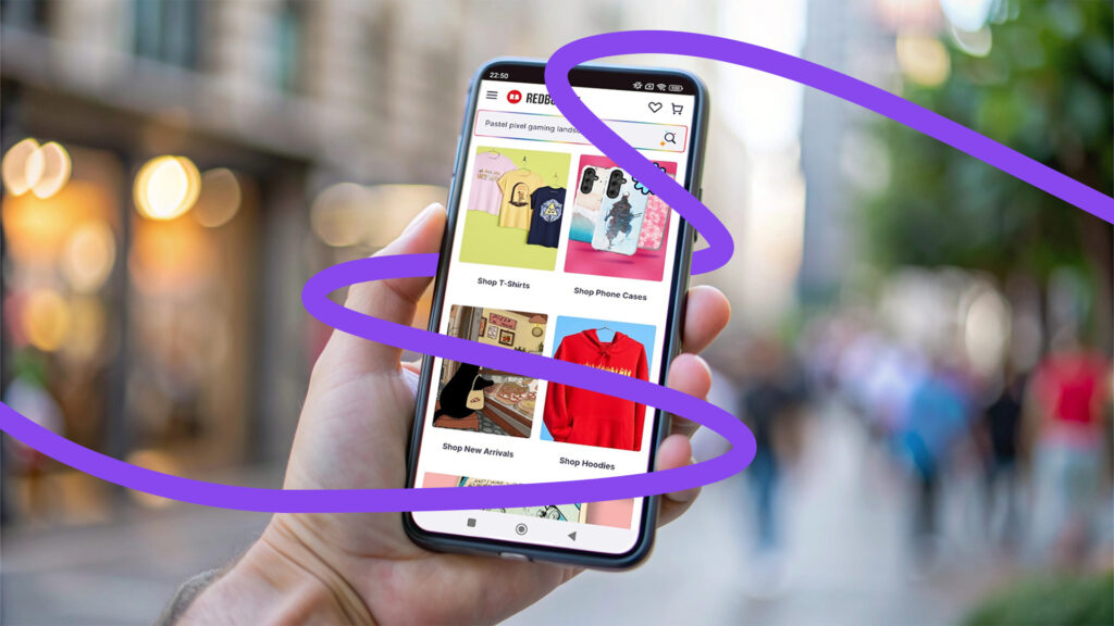 A RedBubble oldala egy mobiltelefonon megnyitva egy vásárló kezében. A képen a Collabri grafikája, egy lila hurok csavarja körbe a mobiltelefont és a vásárló kezét.